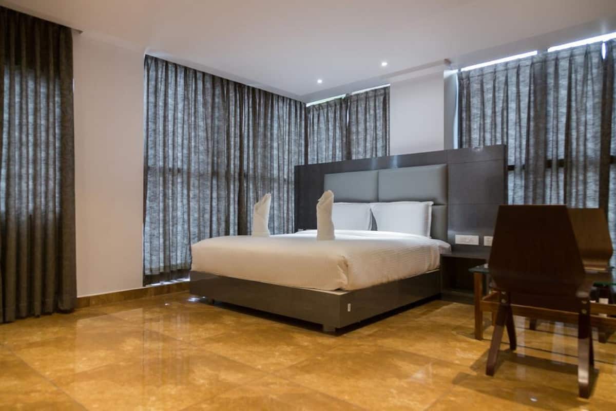 A modern hotel room with a large bed, a desk, and a chair.