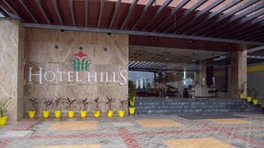 Entrada de un hotel con un cartel grande que dice "Hotel Hills" y un piso de baldosas con un diseño geométrico.