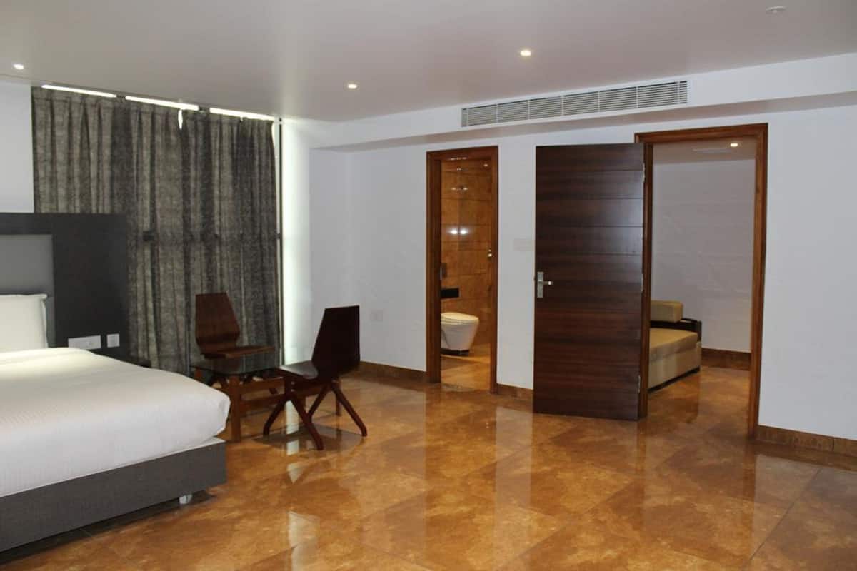 A modern hotel room with a large bed, a desk, and a bathroom visible through an open door.