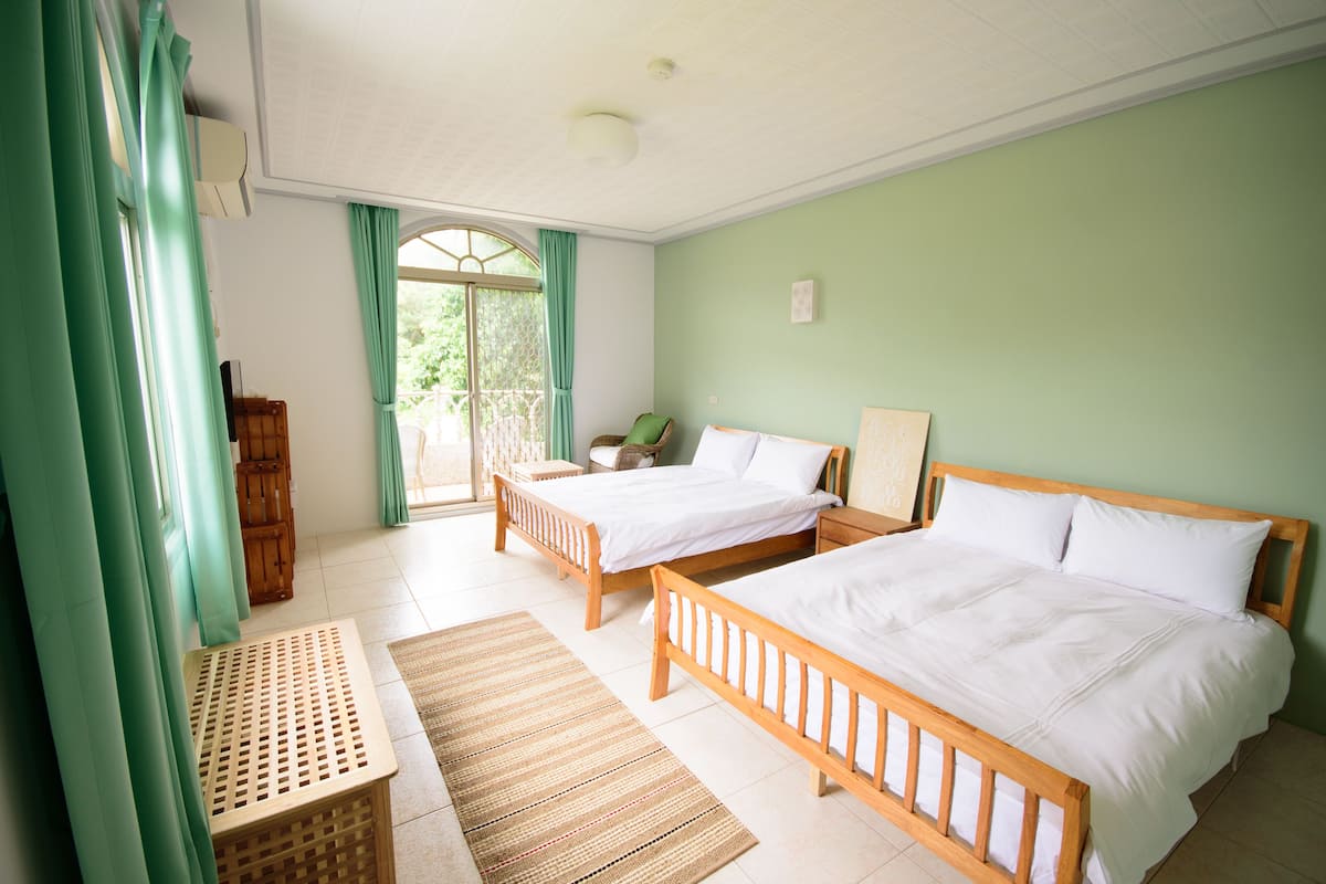 A room with two wooden beds, a small table, and a window with curtains.