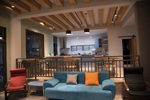 A modern interior with a blue sofa, red and black chairs, a small round table, and a kitchen area in the background. - Green 58 B&B (Hengchun)