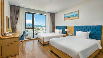 A hotel room with two beds, a desk, and a large window with a city view.