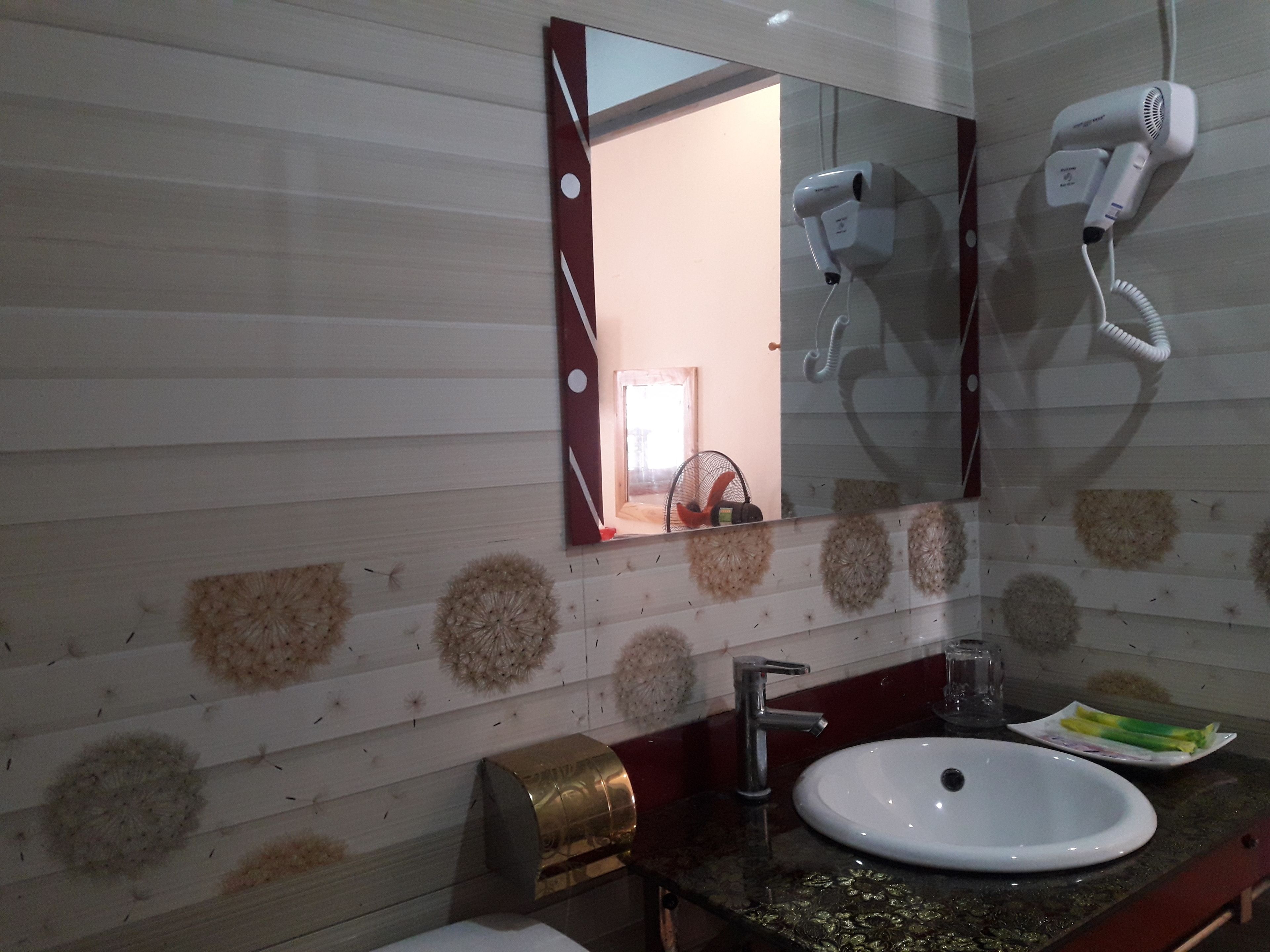 A bathroom with a white sink, a mirror, and two hair dryers mounted on the wall.