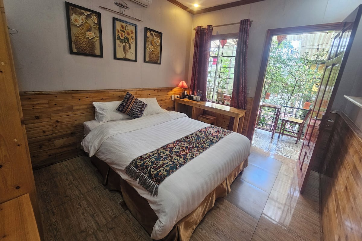 A room with a wooden bed, a nightstand with a lamp, and a window with curtains.