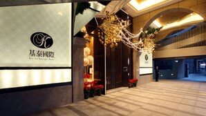 A hotel entrance with a modern design, featuring a logo and name on the wall, a decorative archway, and a checkered floor. - Taipei K House (Taipei)
