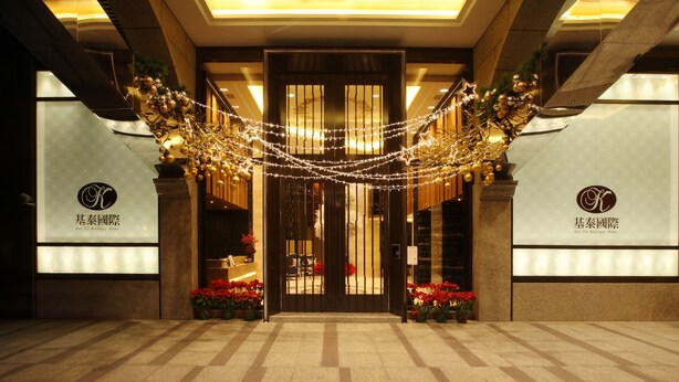 A hotel entrance with a modern design, featuring a large glass door, decorative lights, and potted plants. - Taipei K House (Taipei)