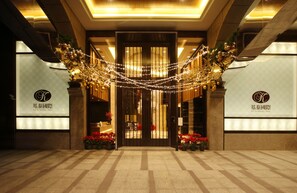 A hotel entrance with a modern design, featuring a large glass door, decorative lights, and potted plants. - Taipei K House (Taipei)