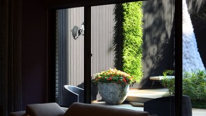 A modern interior with a sofa, a potted plant, and a view of an outdoor area with a vertical garden and a table. - Taipei K House (Taipei)