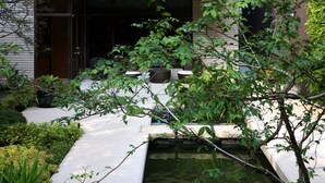 A serene garden with a small pond, a wooden deck, and various plants. - Taipei K House (Taipei)