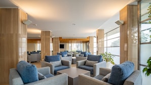 Eine großzügige Lobby mit modernen Möbeln, großen Fenstern und einem Flachbildfernseher.