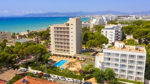 Ein Hotel mit Dachpool, umgeben von Grün und Blick aufs Meer.