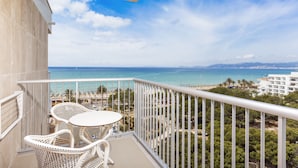 Ein Balkon mit Korbmöbeln und Blick auf Strand und Meer.