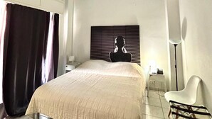 Een slaapkamer met een bed, een hoofdbord met een silhouet, een stoel, een nachtkastje en een lamp.