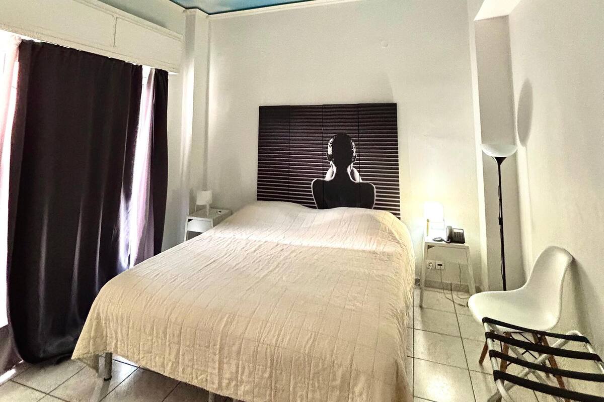 A bedroom with a bed, a headboard with a silhouette, a chair, a nightstand, and a lamp.