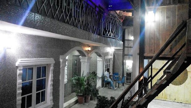 A hotel interior with a balcony, outdoor seating area, and a staircase. - Hotel Princebella (Lagos)