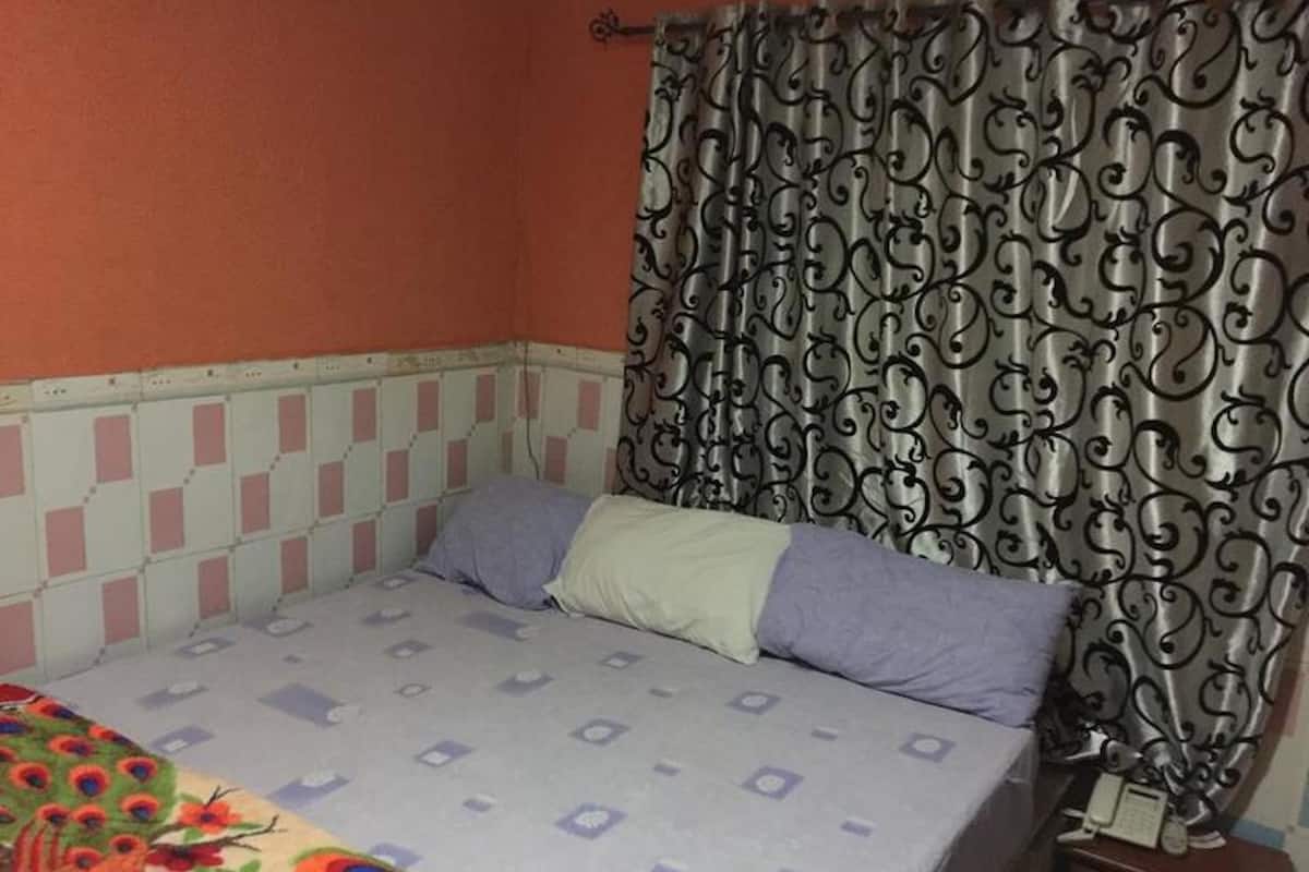 Una habitación con una cama, una cortina estampada y un teléfono en la mesita de noche.