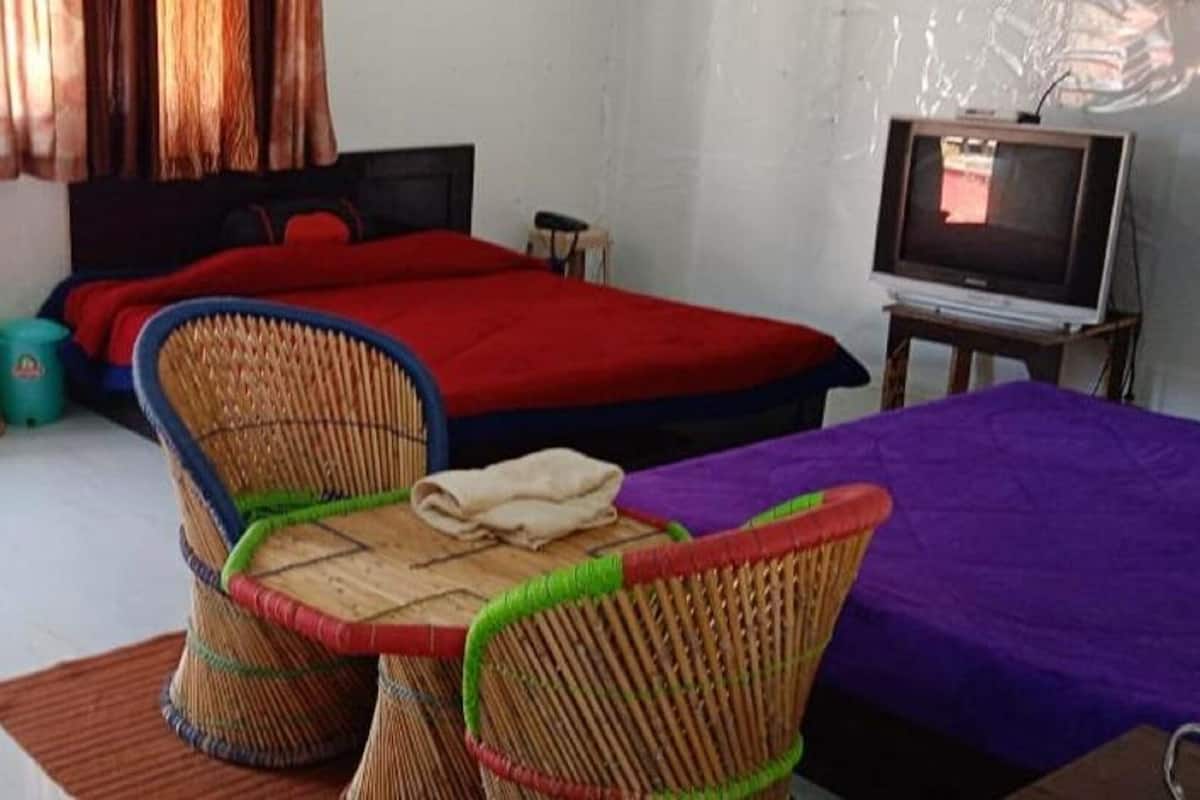 A room with a bed, a television, wicker chairs, and a small table.