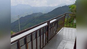 Un balcon doté d’une balustrade en métal, d’où l’on peut admirer un paysage montagneux.
