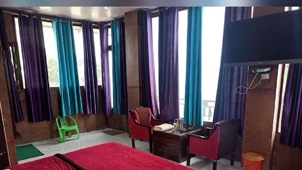 Une chambre d’hôtel équipée d’un lit, d’un bureau, d’une chaise, d’une télévision et d’une fenêtre avec des rideaux.