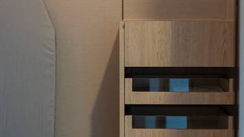A modern bathroom with a wooden vanity, a towel rack, and a shelf with neatly arranged towels.