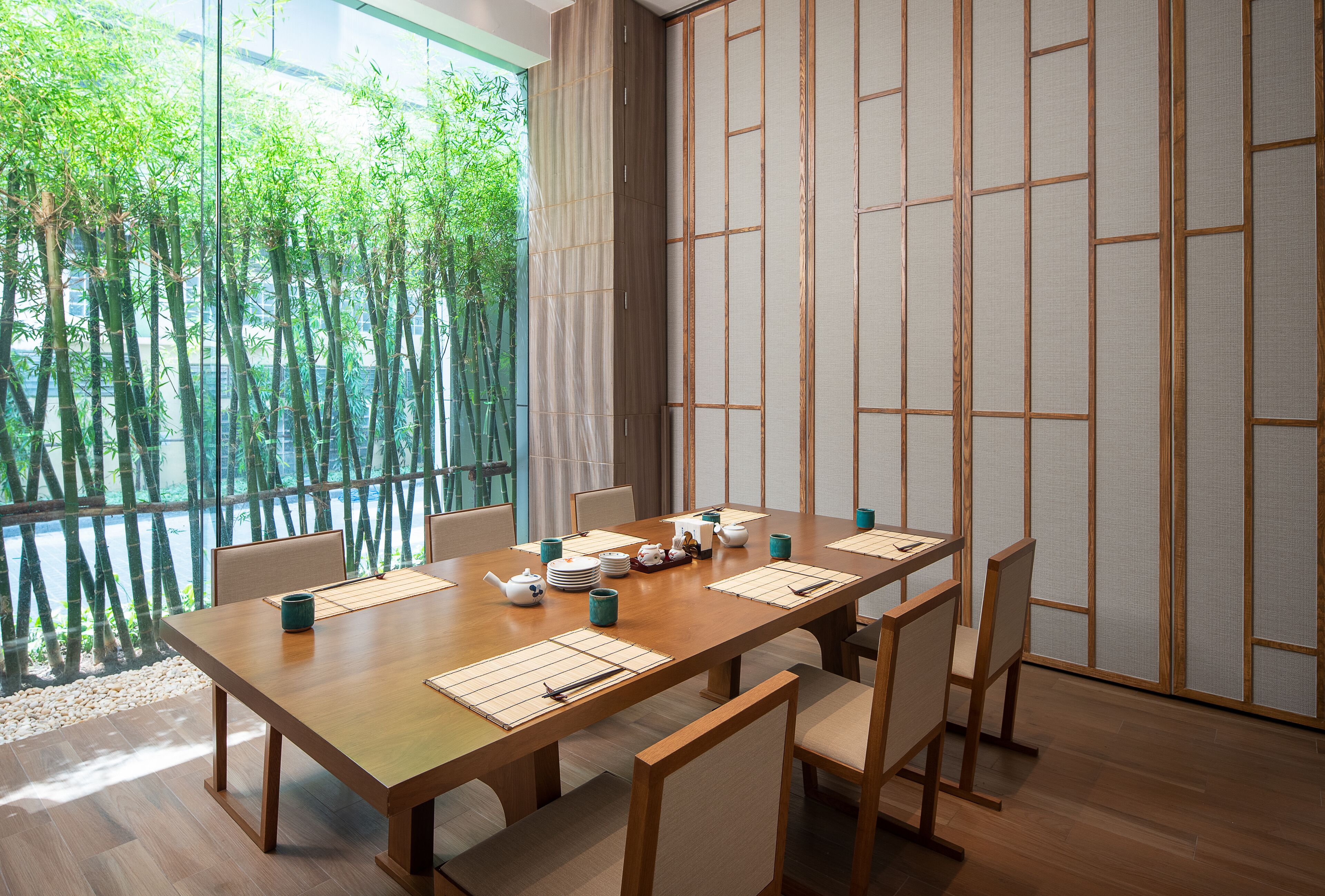 Une salle à manger de style japonais traditionnel, avec une table en bois dressée pour six personnes, entourée de tatamis et de paravents shoji.
