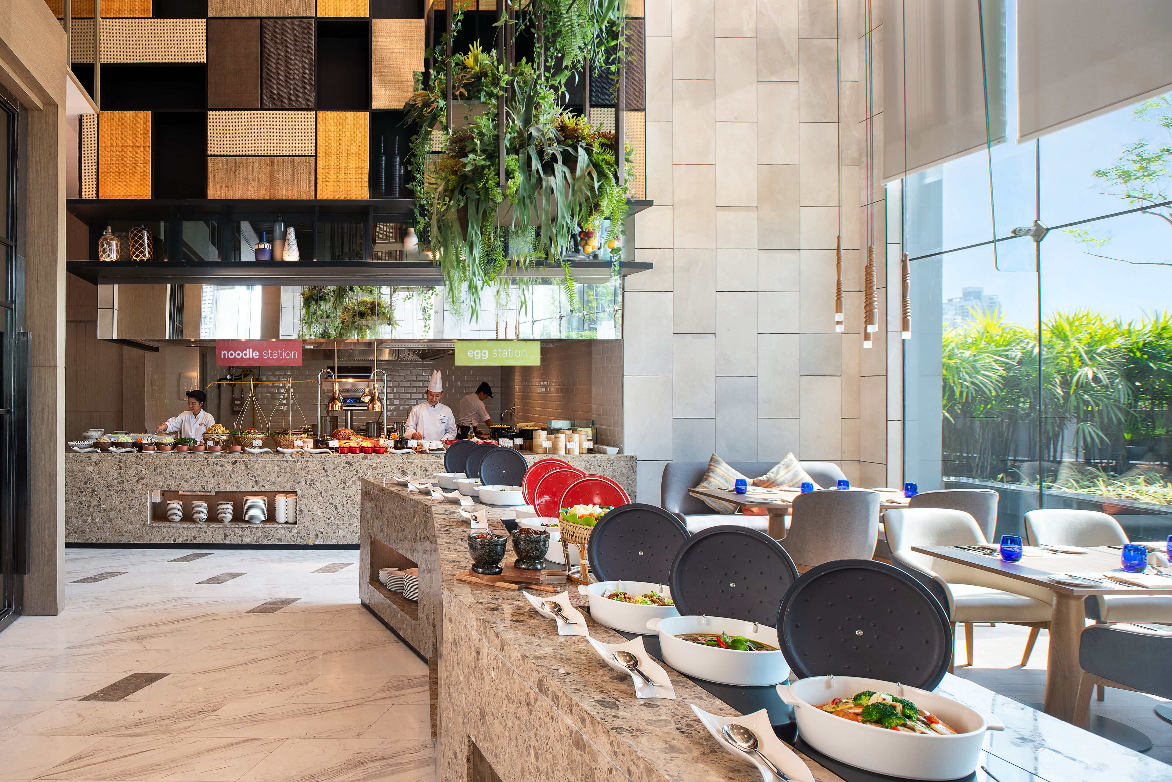 Un restaurant moderne avec un long comptoir, proposant une variété de plats, et où un chef prépare les repas.