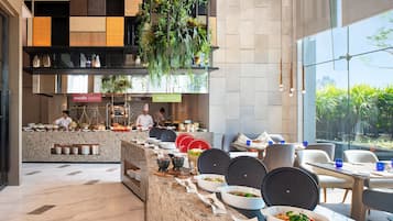 A modern restaurant with a long counter, various dishes, and a chef preparing food.