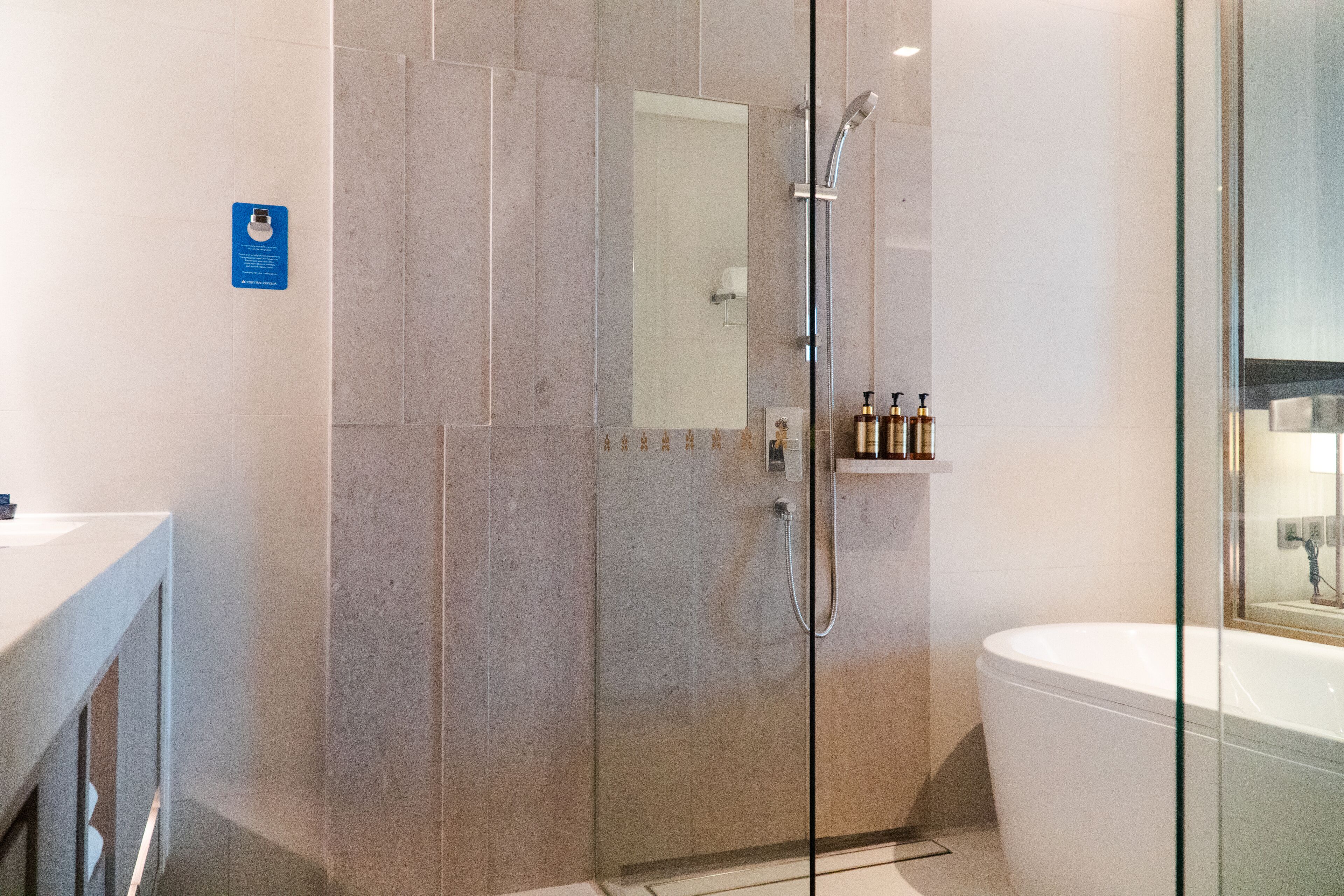 A modern bathroom with a glass-enclosed shower, a white bathtub, and a vanity with toiletries.