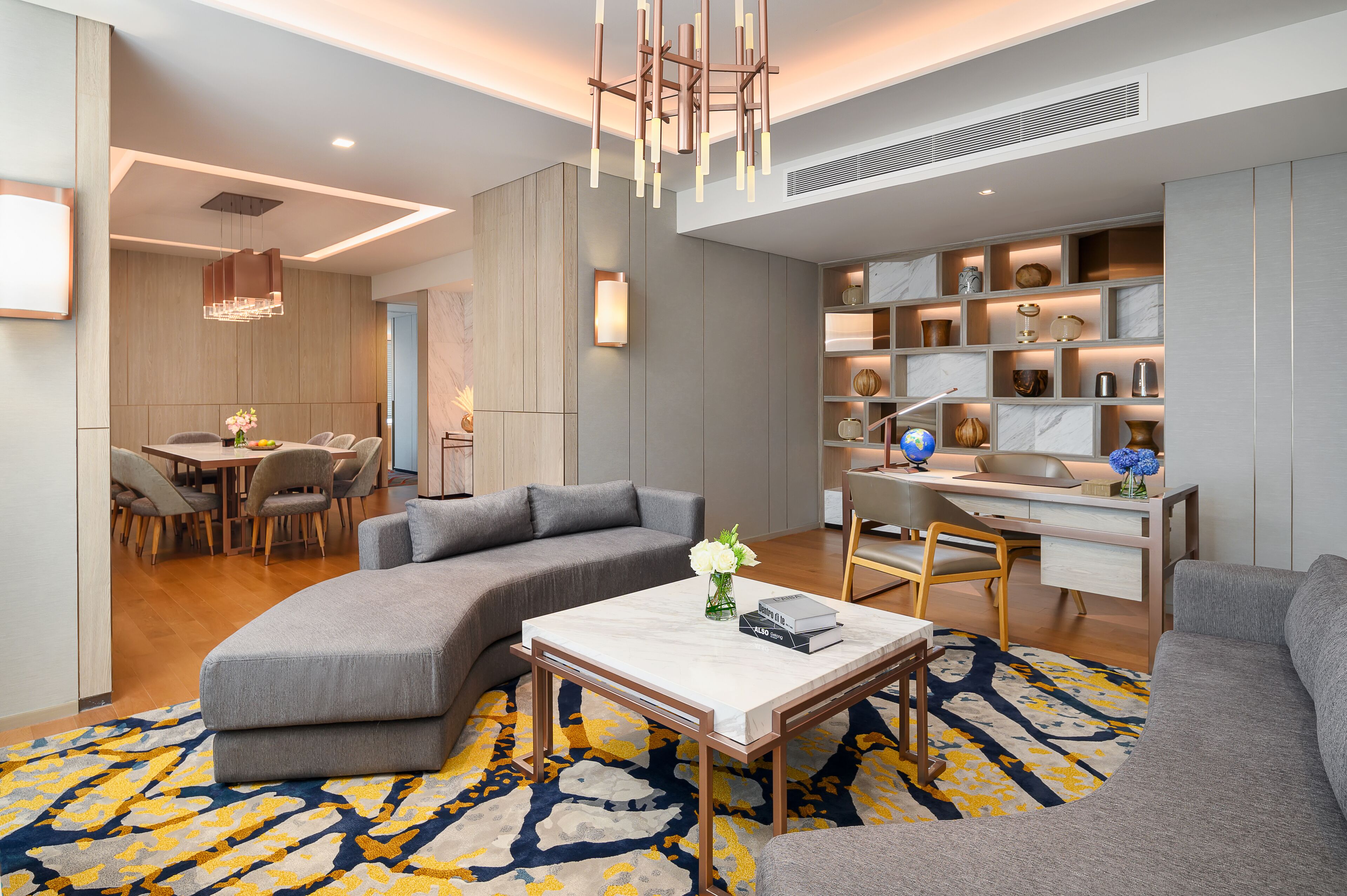 A modern living room with a sectional sofa, a coffee table, and a dining area with a wooden table and chairs.