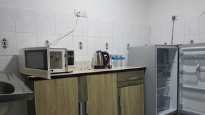 A kitchen with a microwave, coffee maker, and refrigerator. - Anjung Apartment 3BR 1 (Banting)
