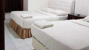 A hotel room with two beds, a bedside table, an air conditioning unit, and a door with curtains. - Anjung Apartment 3BR 1 (Banting)