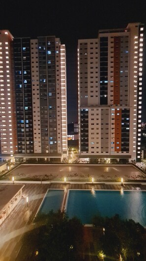 A nighttime view of a residential building complex with multiple high-rise apartments, a swimming pool, and well-lit pathways. - Anjung Apartment 3BR 1 (Banting)