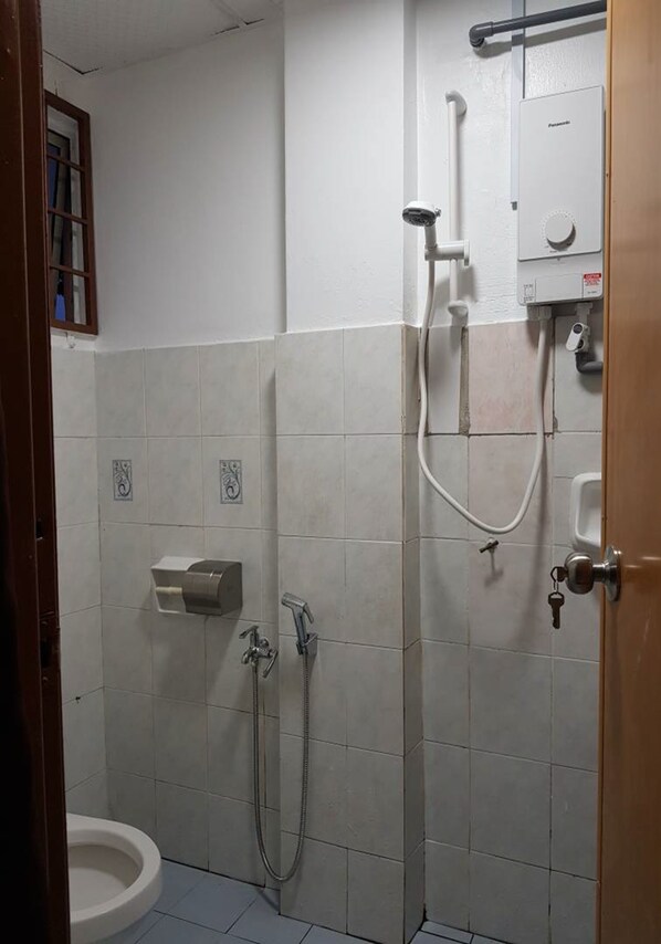 A small, tiled bathroom with a toilet, a sink, and a shower. - Anjung Apartment 3BR 1 (Banting)