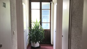 A hallway with a red carpet, white walls, and a large potted plant in the center. - Hôtel des Lacs (Chamonix-Mont-Blanc)