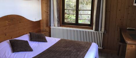 A wooden room with a bed, a window, and a radiator.