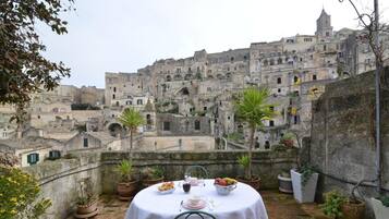 Un tavolo apparecchiato su un terrazzo panoramico con vista su un centro storico caratterizzato da edifici in pietra e una torre.