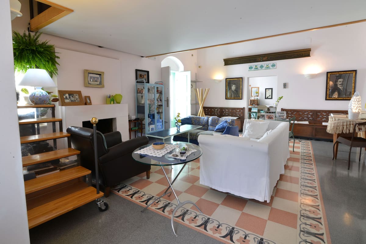 Un salon avec un canapé, une table basse, une cheminée et un escalier.