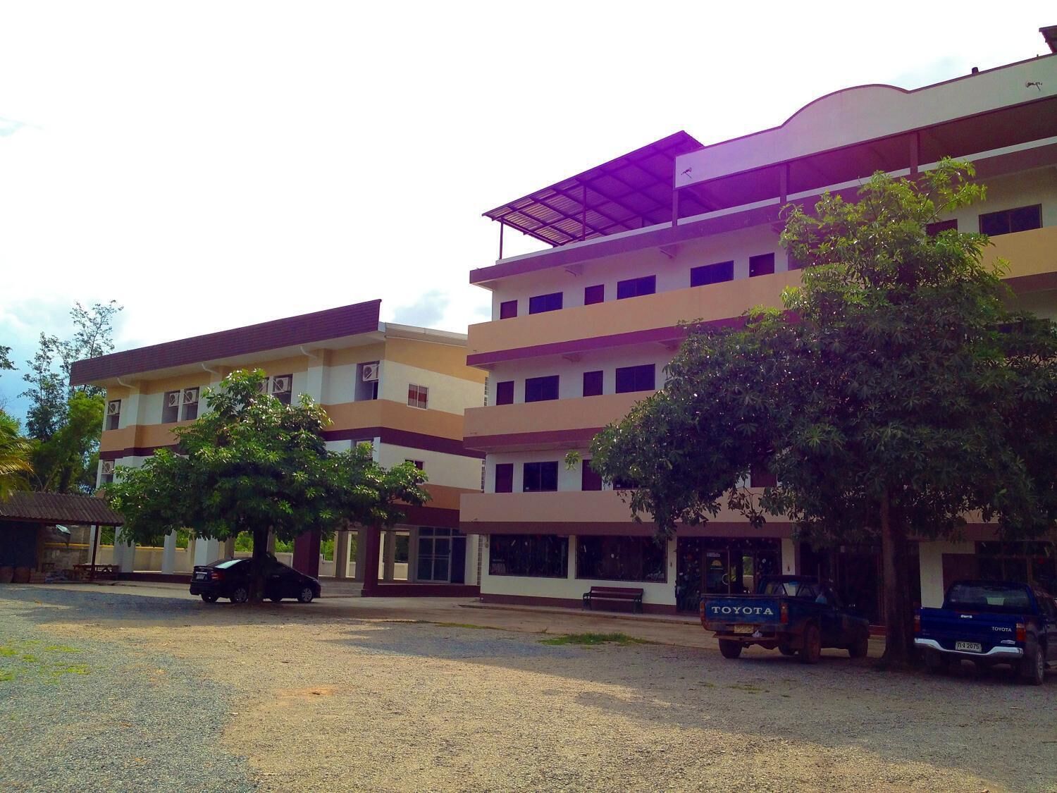 A multi-story building with a flat roof and a parking area in front.