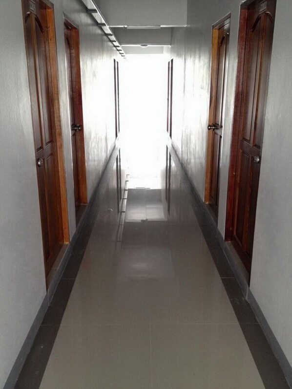 A long, narrow hallway with wooden doors on both sides and a tiled floor.