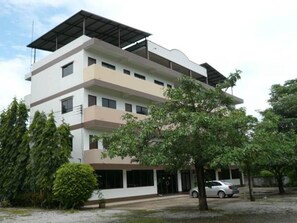 A multi-story building with a flat roof, large windows, and a covered entrance.