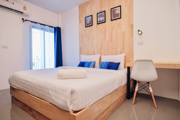 Un dormitorio moderno con una cama de madera, un escritorio y una silla. Hay tres cuadros enmarcados en la pared.