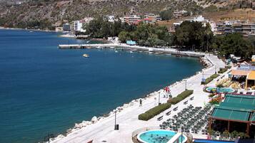 A coastal hotel with a pool, outdoor seating, and a view of the sea.