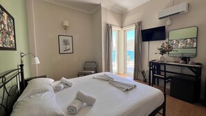 A hotel room with a bed, a desk, a chair, a TV, and a window with curtains. - Grand Hotel Loutraki (Loutraki-Agioi Theodoroi)