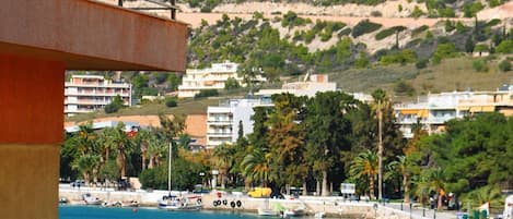 Vista costera con un puerto deportivo, edificios y una ladera.