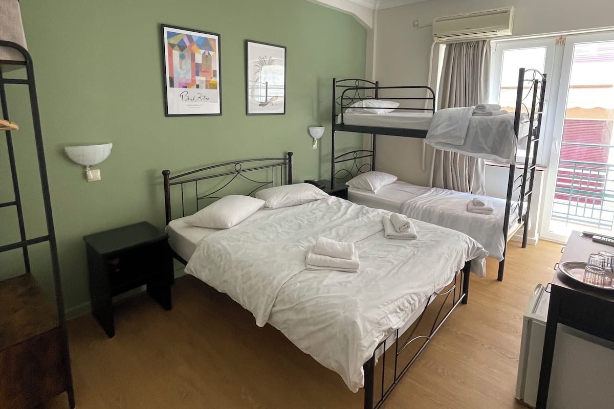 A room with bunk beds, a small bedside table, a lamp, and a window with curtains.