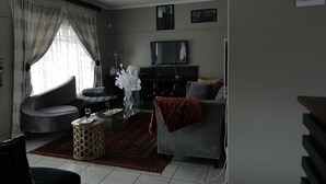 Uma sala de estar com sofá, mesa de centro, televisão e lareira.