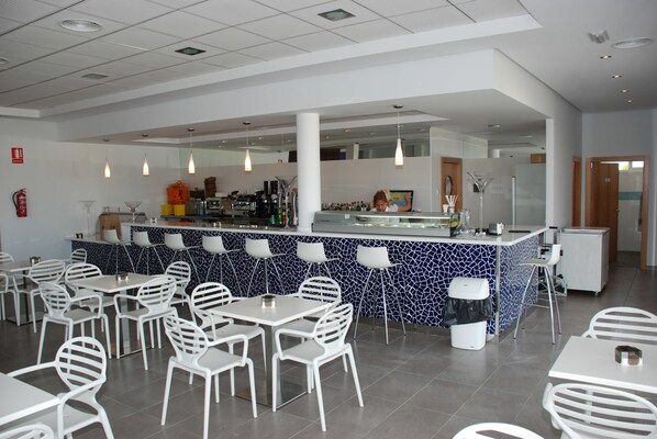 Un restaurante moderno con una barra central, sillas y mesas blancas.
