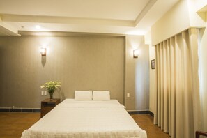 A hotel room with a large bed, a nightstand with a vase of flowers, and a curtain on the window. - My Lan Hanoi Hotel (Hanoi)