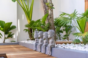 Stroll along the winding pathway surrounded by lush greenery and serene sculptures.