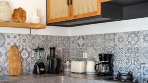 Une cuisine équipée d’un plan de travail en granit, d’un mixeur, d’un grille-pain, d’une machine à café et d’une cuisinière.